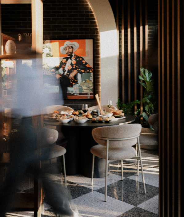 Moderni interijer Porat Pizza & Bar Zadar — okrugli stol s tapas tanjurima, vinskim čašama i umjetničkim portretom na zidu od opeke