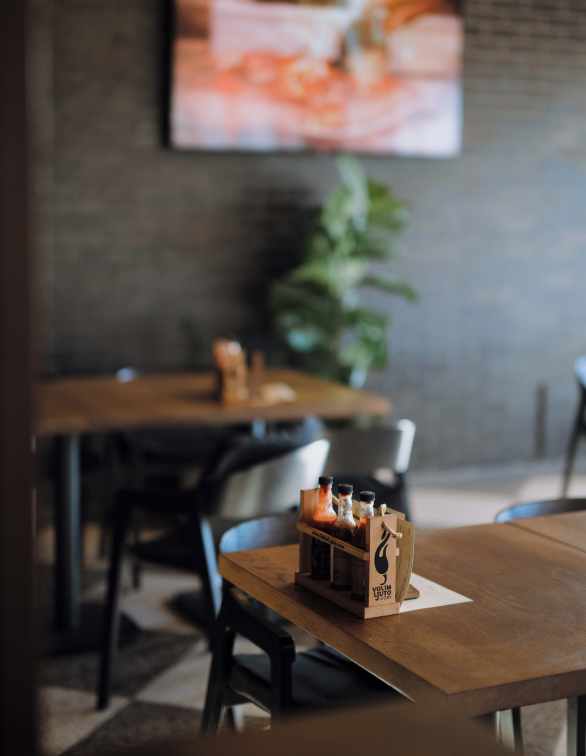 Drveni stol u Porat Pizza & Bar — začini Volim Ljuto, biljke i opečani zid, opušten ambijent za ručak